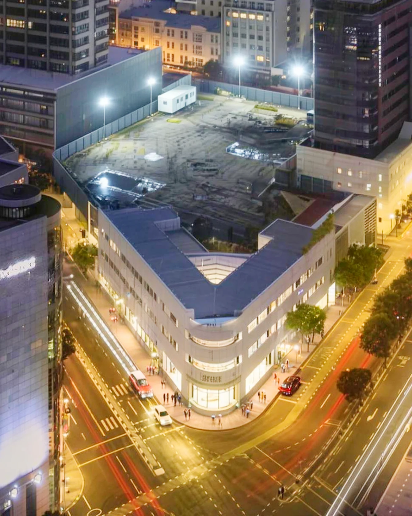 The heritage corner building on its own at night, the cleared site behind it